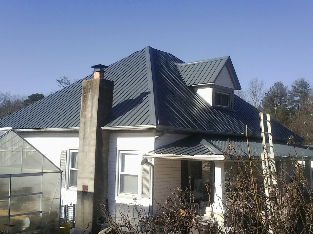 Dark blue standing seam metal roof on a white farmhouse with dormer — Slate & Tile Roof Repair by Roofing Brothers in Refton