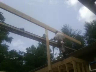 Carpenter setting a ridge beam over a new addition frame — Ice Dam Removal by Roofing Brothers in Refton