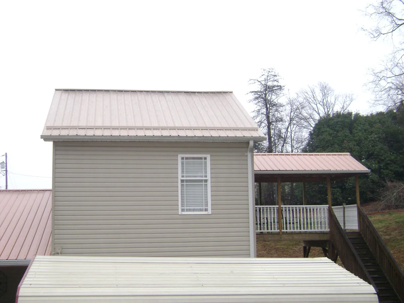 Tan metal roofs on a two story addition and attached porch, from a Roof Replacement job in Refton