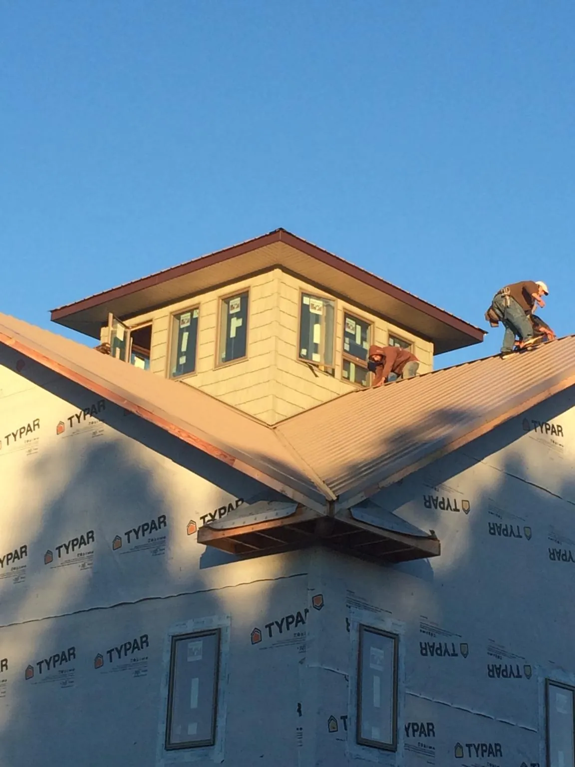 Roofers working around a rooftop cupola on a new metal roof at sunset — Roof Waterproofing in Refton by Roofing Brothers
